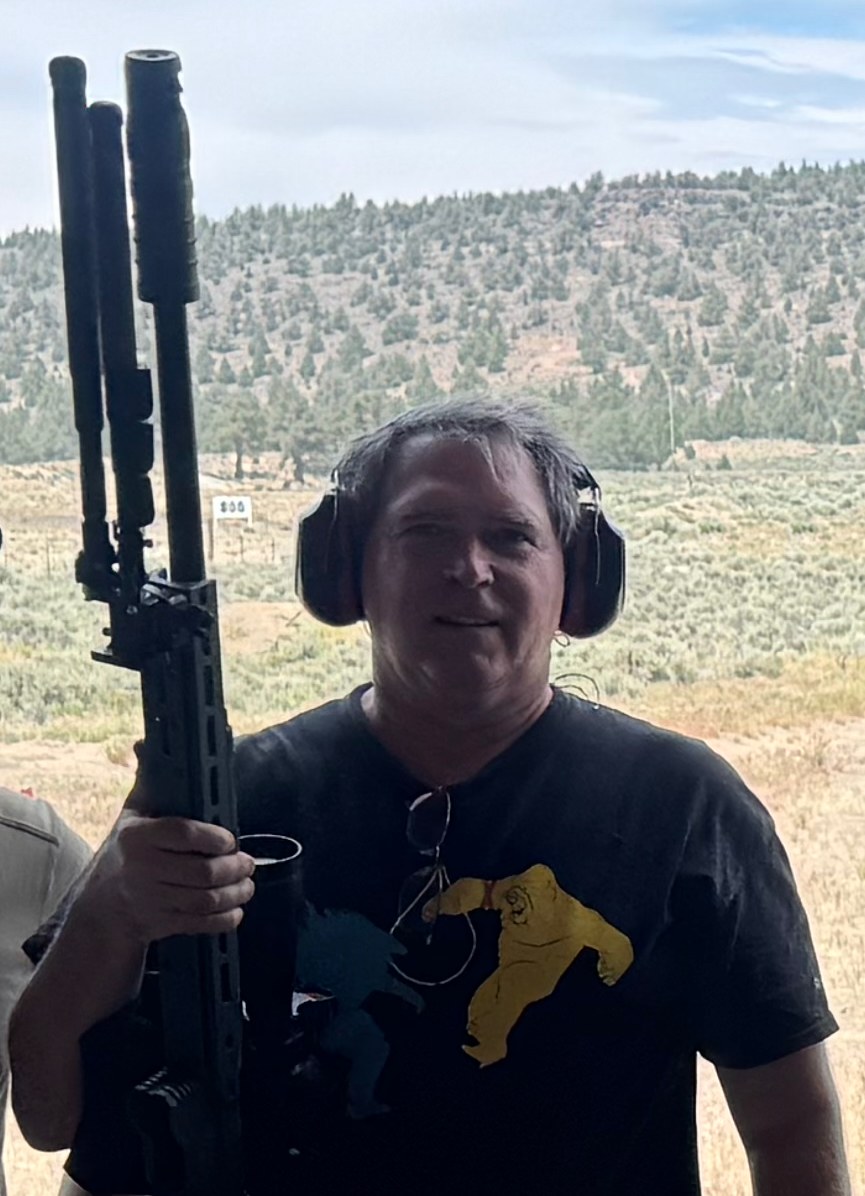 Markus Weltin at a high-desert range, ear protection on, holding a precision rifle